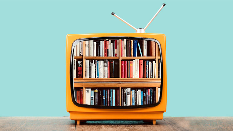 Old style tube TV with rabbit ears showing an image of a wooden bookshelf full of books